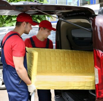 Günstig umziehen in Castrop-Rauxel Günstig umziehen in Castrop-Rauxel: Umzugshelfer laden ein gelbes Sofa in einen Transporter