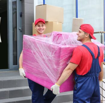 Umzug in Castrop-Rauxel Zwei Umzugshelfer tragen ein in Folie gepacktes Möbelstück – Umzug in Castrop-Rauxel
