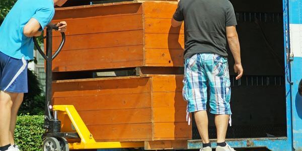 Möbellift Castrop-Rauxel: Zwei Helfer tragen einen Holzschrank aus einem Lkw